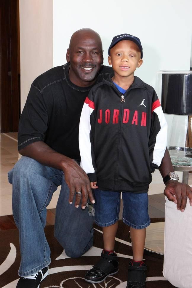 Michael Jordan kneeling beside a young boy wearing a Jordan-branded jacket and cap